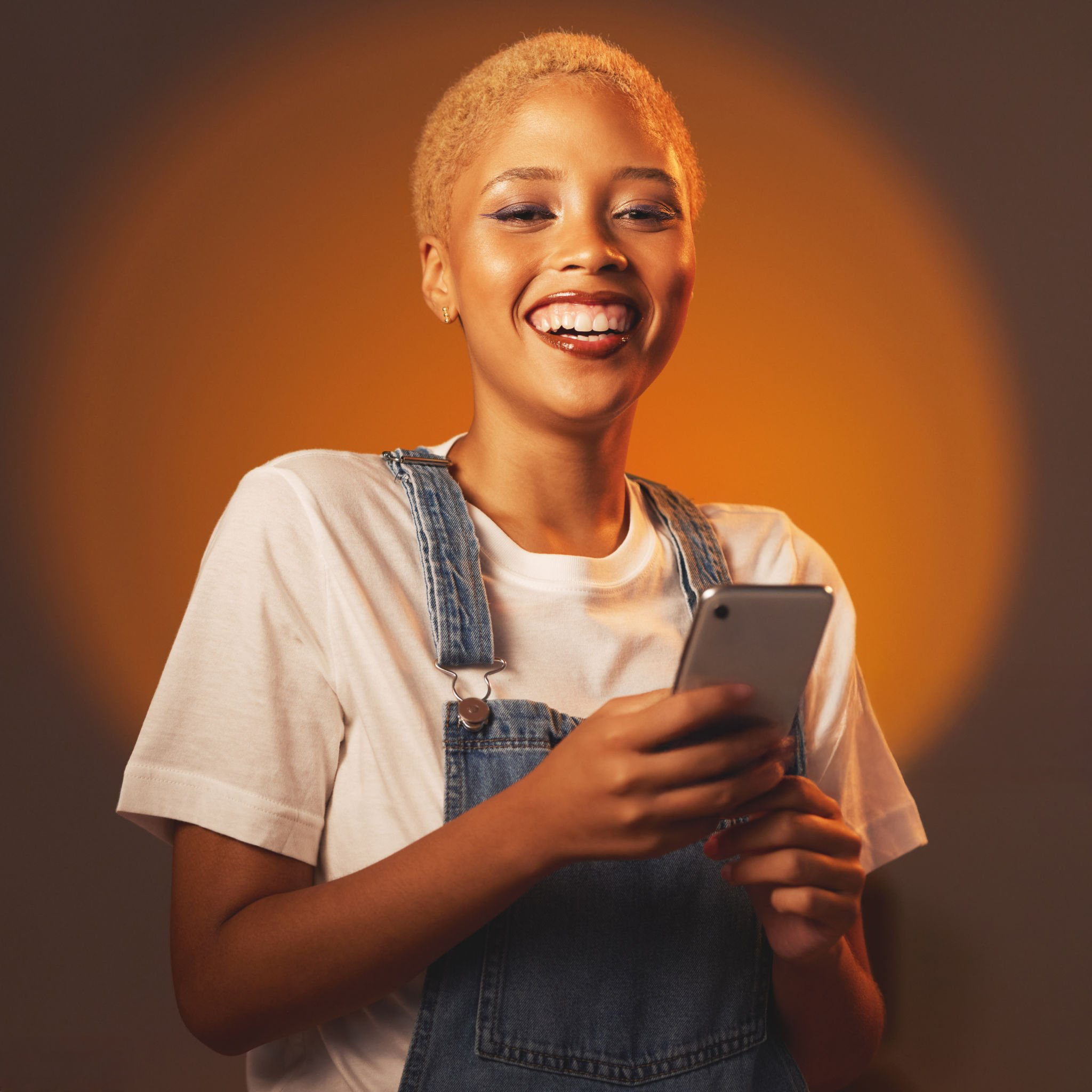 A young Ugandan woman smiling while using her phone
